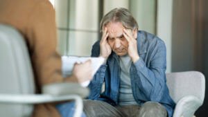 A counselor talks with a senior patient and takes notes.