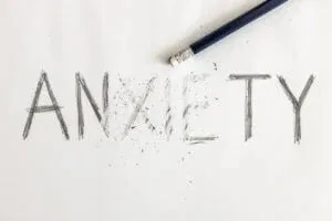 The word "anxiety" written on paper with part of it erased, symbolizing overcoming anxiety