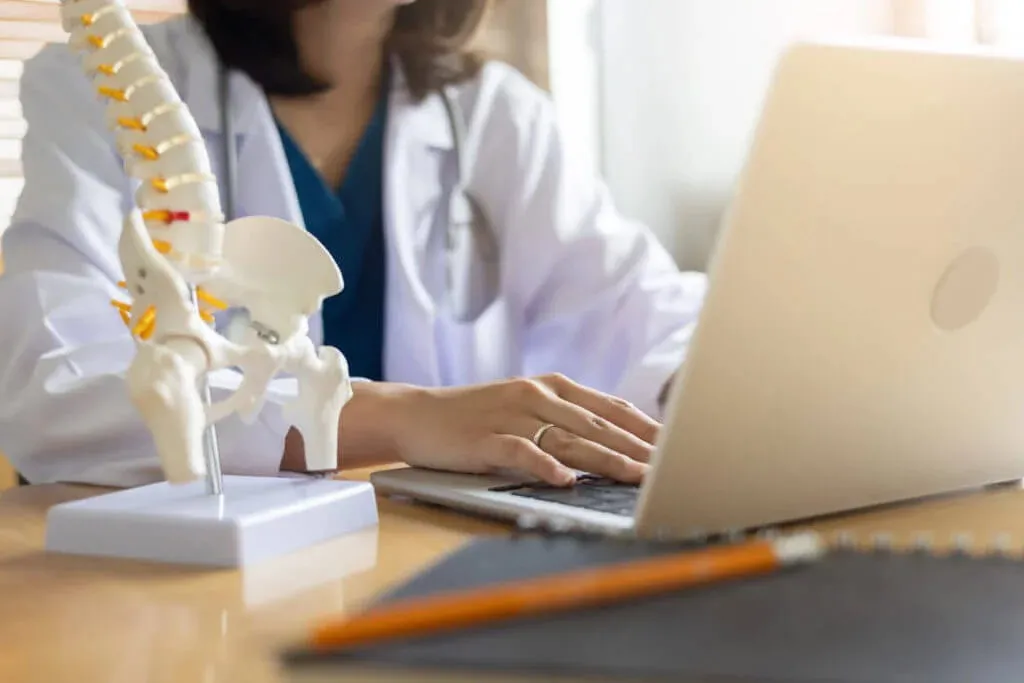A healthcare provider references a spine and hip model while reviewing bone health information for a bone density test consultation