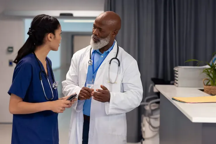 Doctor and nurse discussing a patient's care plan in a clinical hallway