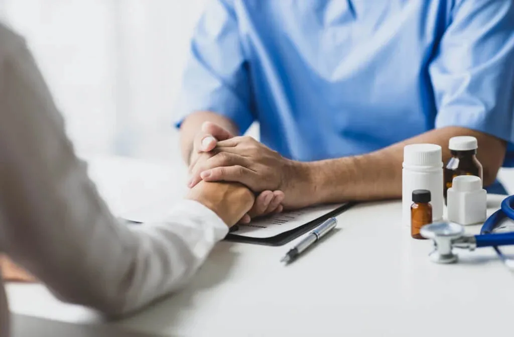 An Abundance Health Care provider holds a patient's hand for reassurance during a mental health assessment in Colorado Springs