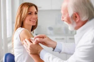 A doctor administers a vaccine to a smiling patient during a visit to Abundance Health Care