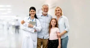 A family medicine provider at Abundance Health Care meets with a smiling mother, father, and daughter in Colorado Springs