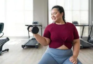 A woman lifts a dumbbell during a strength-training session as part of a healthy weight loss plan
