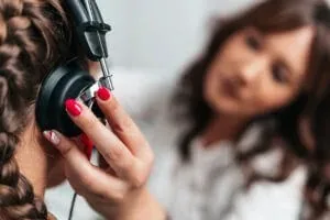 A provider holds an audiometer headphone to a patient's ear during a hearing test
