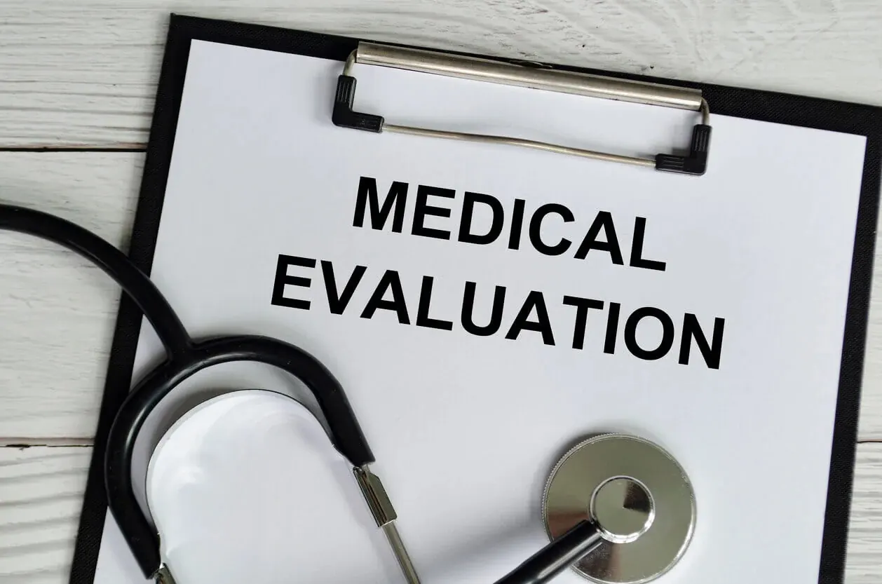 Medical evaluation notes written on a white paper clipboard accompanied by a stethoscope on a wooden table