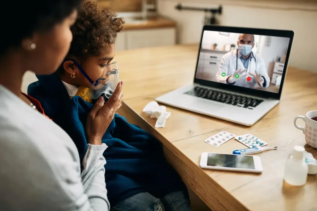 Mother comforting her daughter during a pediatric telehealth video call with a doctor
