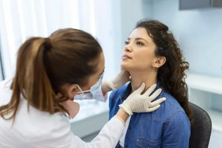 A doctor examines a patient's throat and neck during a sore throat evaluation