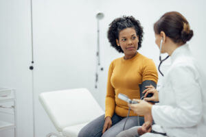 Family Nurse Practitioner measuring blood pressure to a smiling woman